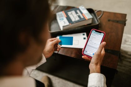 Pessoa realiza um pagamento online com um smartphone e um cartão de crédito em ambiente interno.