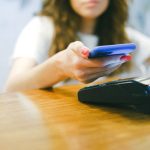 Mulher aproxima o smartphone de um terminal para realizar um pagamento por aproximação.