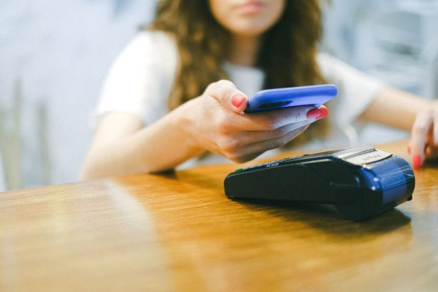 Mulher aproxima o smartphone de um terminal para realizar um pagamento por aproximação.