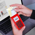 Mulher usa um gerador de códigos de segurança para autenticar um pagamento online no laptop.