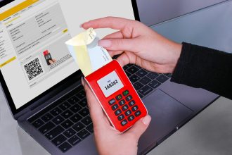 Mulher usa um gerador de códigos de segurança para autenticar um pagamento online no laptop.