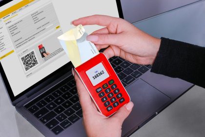 Mulher usa um gerador de códigos de segurança para autenticar um pagamento online no laptop.