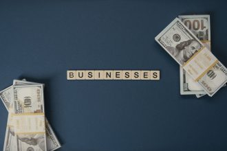 Cédulas de dólar dispostas ao lado de peças com a palavra “businesses”, em referência a negócios e transações financeiras.